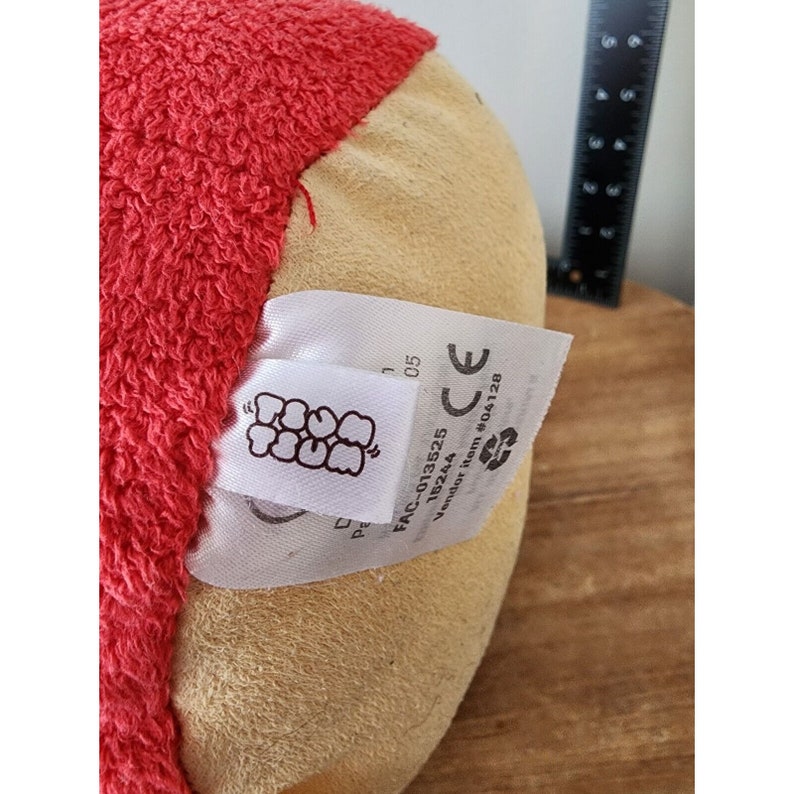 May include: A red and beige plush toy with a tag that reads "FAC-013525 1B244 Vendor Item #104128 CE".