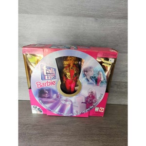 Könnte beinhalten: Eine rosa und goldene Box mit einer CD-ROM im Inneren. Die Box zeigt eine Barbie-Puppe in einem roten und goldenen Outfit und den Text "Talk with me! Barbie". Der Text "Now you can program me to talk and we can play like never before!" ist ebenfalls auf der Box zu sehen.