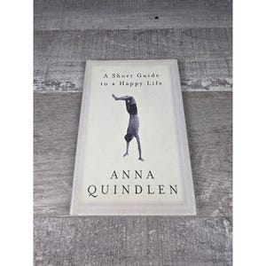 以下が含まれることがあります： アンナ・クィンドレン著『A Short Guide to a Happy Life』のハードカバー本。オフホワイトの表紙の中央には、逆立ちをしている人物の白黒イラストが描かれており、タイトルと著者名が黒い文字で印刷されています。
