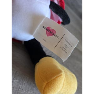 May include: A plush toy featuring a white body, black accents, and a yellow hand. A tag with the text "KOHL'S cares" and a heart logo is attached. The toy is a Disney product.