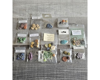 May include: Assortment of small ceramic beads and charms in various colors and designs, packaged in clear plastic bags. Some bags have labels with names and websites.