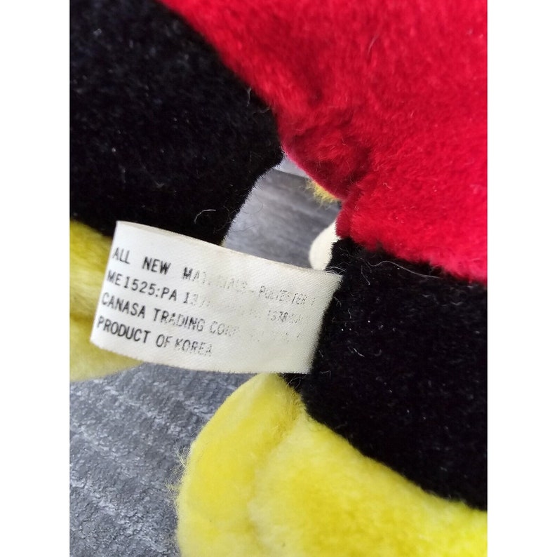 May include: A yellow, black and red plush bee toy with a white tag that reads "ALL NEW MADE IN KOREA - POLYESTER 100% - 137844 - CANASA TRADING CORP. PRODUCT OF KOREA."