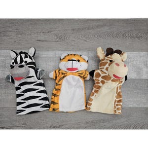 May include: Three plush hand puppets: a zebra with black and white stripes, a tiger with orange and black stripes, and a giraffe with brown spots. Each puppet has a smiling face and is designed for children's play.