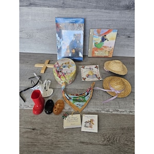 Può includere: Una collezione di articoli a tema orsacchiotto. Gli articoli includono un libro, un diario, un puzzle, una scatola di latta, un cappello, una sciarpa, un paio di scarpe, un paio di stivali e una bambola. Gli articoli sono tutti in varie tonalità di marrone, rosso, blu e giallo.