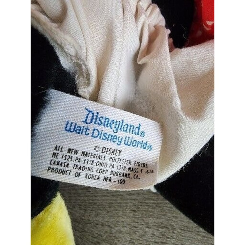 Pu&ograve; includere: Peluche bianca con un motivo bianco e nero. Il giocattolo ha un'etichetta che recita "Disneyland Walt Disney World" e "Tutti i nuovi materiali in fibra di poliestere ME 1525 PA 1378-Ohio PA 1378-Mass 1-616 Camasa Trading Corp Burbank, CA. Prodotto in Corea MFR-100."