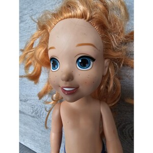 May include: A red-haired doll with blue eyes and freckles. The doll is wearing a blue swimsuit and has a bare torso.