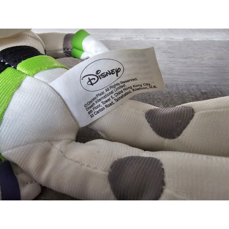 Peut inclure: Un jouet en peluche blanc de Buzz l'&Eacute;clair de la franchise Toy Story. Le jouet a des d&eacute;tails noirs et verts sur sa combinaison et des points gris sur son corps. Le jouet a une &eacute;tiquette attach&eacute;e &agrave; lui qui indique "Disney/Pixar, Tous droits r&eacute;serv&eacute;s. Dream International Limited. 8&egrave;me &eacute;tage, Tour 5, China Hong Kong City, 33 Canton Road, Tsimshatsui, Kowloon, H.K."