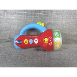 May include: A red and blue VTech Spin & Learn Color Flashlight toy. The toy has a blue handle, a red light, and several buttons with icons and the letters ABC. The flashlight has a clear, rotating section with colourful images.