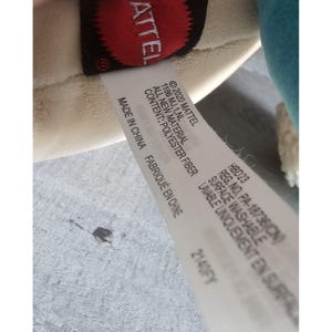 May include: White tag with black text that reads "&copy;2020 Mattel 1186 MJ,1,NL All New Material Content: Polyester Fiber Made in China Fabriqu&eacute; en Chine HBD23 Reg. No. PA-18736 (CN) Surface Washable Lavable Uniquement en Surface 2140FY"