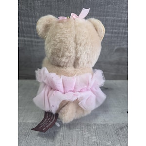 Pu&ograve; includere: Un orsacchiotto beige con un tut&ugrave; rosa e un fiocco rosa. Il tut&ugrave; &egrave; fatto di strati di tulle rosa con un design scintillante. L'orso ha un piccolo fiocco rosa sulla testa. Un'etichetta marrone &egrave; attaccata all'orso.