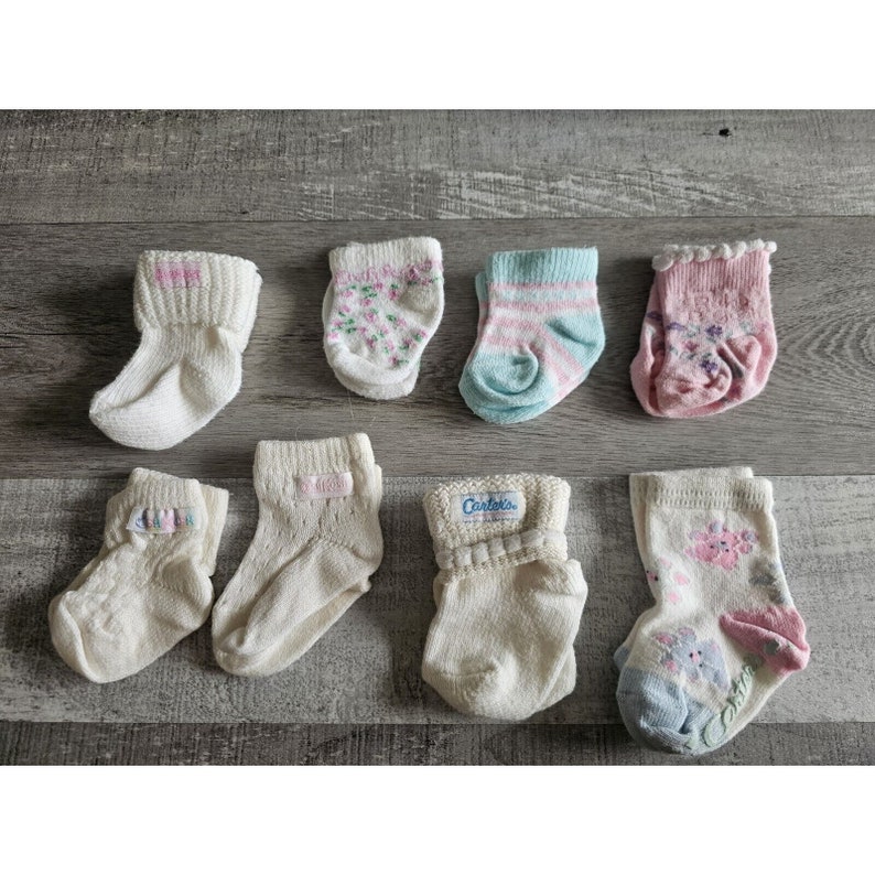 Puede incluir: Una colecci&oacute;n de ocho calcetines para beb&eacute; en varios colores y patrones, incluyendo blanco, rosa, azul y dise&ntilde;os florales. Algunos calcetines llevan el nombre de la marca "Carter's".