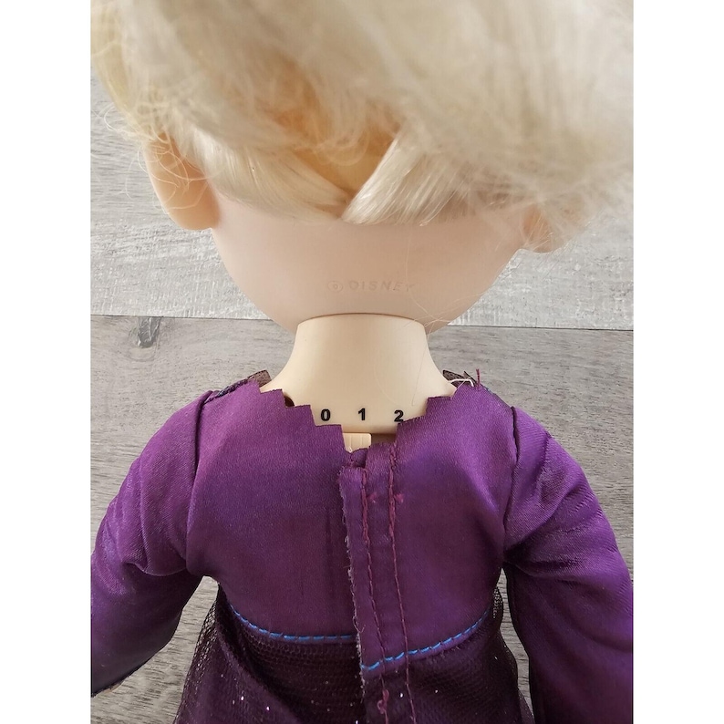 May include: A purple dress with a sparkly skirt and long sleeves. The dress has a seam down the back with numbers 0, 1, and 2 marked on it.