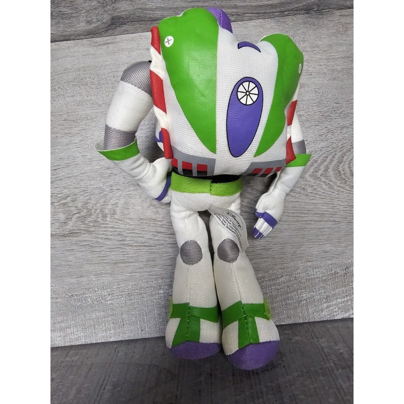 Peut inclure: Un jouet en peluche blanc, vert et violet de Buzz l'&Eacute;clair de la franchise Toy Story. Le jouet est debout, les bras tendus, et a une grosse t&ecirc;te ronde avec une visi&egrave;re violette.