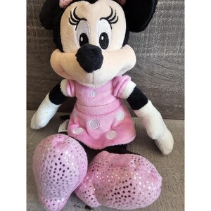 May include: A pink and black plush toy of Minnie Mouse wearing a pink polka dot dress with sparkly pink shoes.