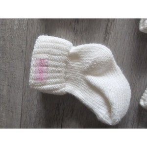 Puede incluir: Calcetines de beb&eacute; de punto blanco con una etiqueta rosa que dice "Little Feet".