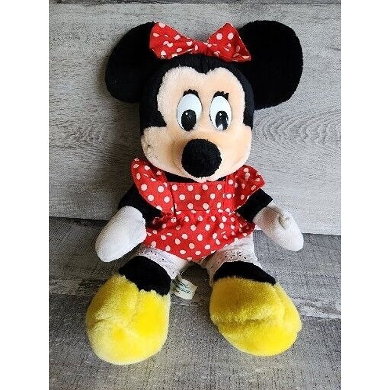 Peut inclure: Un jouet en peluche repr&eacute;sentant Minnie Mouse, la petite amie de Mickey Mouse. Elle porte une robe rouge &agrave; pois blancs et un n&oelig;ud blanc. Elle a des oreilles noires et un nez noir.