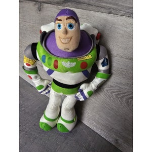 Peut inclure: Un jouet en peluche de Buzz l'&Eacute;clair de la franchise Toy Story. Le jouet porte sa combinaison de ranger spatial signature avec un casque violet et des accents verts et blancs. Le jouet a un visage blanc avec des yeux bleus et un sourire amical. Le jouet tient ses bras &eacute;cart&eacute;s et a une base verte et blanche.