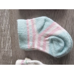 Puede incluir: Un par de calcetines para beb&eacute; con un patr&oacute;n de rayas azul claro y rosa.