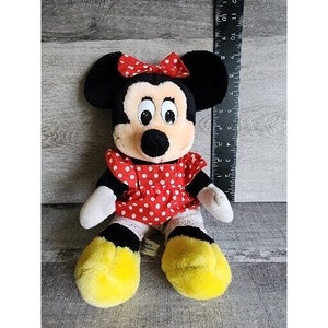 Peut inclure: Un jouet en peluche de Minnie Mouse, la petite amie de Mickey Mouse. Elle porte une robe rouge &agrave; pois blancs et un n&oelig;ud rouge. Elle a des yeux noirs et un nez noir.