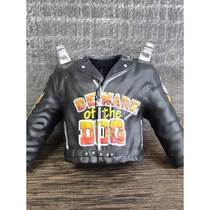 May include: Black leather jacket with the text "BEWARE of the DOG" in yellow and red. The jacket has a zipper closure and silver accents. The sleeves have yellow and orange flame designs. A unique collectible.