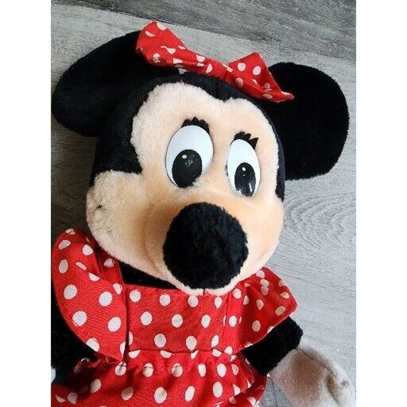 Peut inclure: Un jouet en peluche repr&eacute;sentant Minnie Mouse, la petite amie de Mickey Mouse. Elle porte une robe rouge &agrave; pois blancs et un n&oelig;ud rouge sur la t&ecirc;te. Ses yeux sont grands et noirs, et son nez est noir.