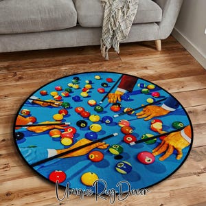 May include: A round rug featuring a vibrant illustration of a pool table with scattered billiard balls and cues. The design includes hands in gloves, creating a playful and colorful aesthetic. The rug has a black border.
