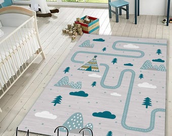 Puede incluir: Una alfombra gris claro con un diseño de carretera, montañas, nubes y árboles en verde azulado y blanco. La alfombra presenta un diseño de tipi y el texto "Unique Rug Decor". Diseñada para una habitación infantil.