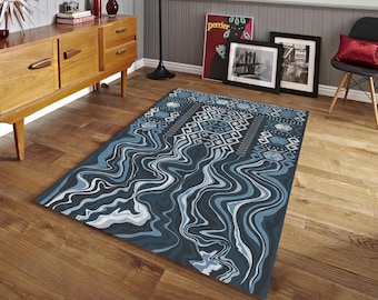 May include: A rectangular area rug with a blue and white abstract design. The rug features a pattern of wavy lines and geometric shapes in shades of blue, gray, and white. The rug is placed on a hardwood floor.