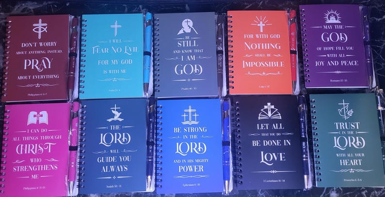 Colorful spiral notebooks with matching sturdy pens displaying Christian bible verses