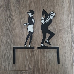 Puede incluir: Silueta en blanco y negro de una pareja bailando en una estantería de metal negro. La mujer lleva una falda y el hombre lleva un traje.