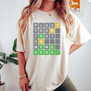 May include: A beige t-shirt with a green and yellow graphic that says "PLACE YOUR TEXT OR MEME HERE!"