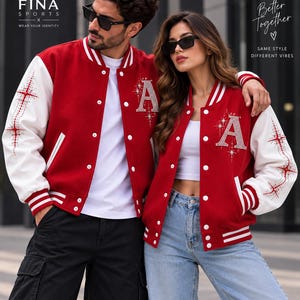 May include: Red and white varsity jackets featuring a rhinestone letter A on the chest and star patterns on the sleeves. The jackets have white snap buttons, striped ribbed cuffs, and collars. Text on the image includes FINA SPORTS and Better Together.