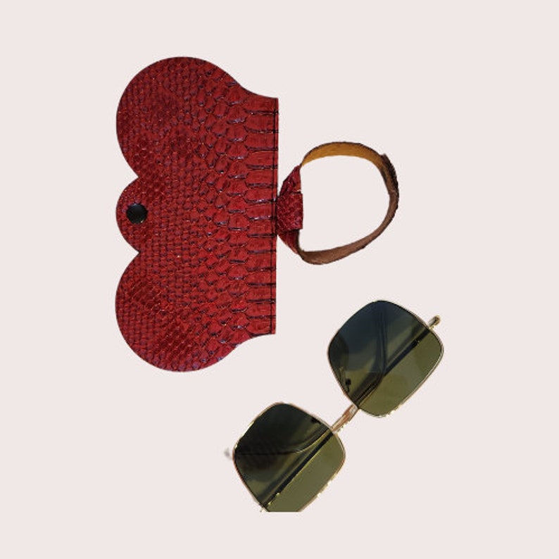 Navigate your day with ease: the ArdenRunway red leopard-print eyewear case, with its handy strap, snaps onto your bag for on-the-spot accessibility. #EffortlessElegance