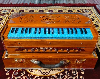 Könnte beinhalten: Ein braunes Holzharmonium mit einer blauen Tastatur und dem Text "National Music" auf der Oberseite. Das Harmonium befindet sich in einem Transportkoffer mit einem schwarzen Griff.