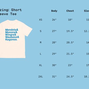 May include: Sizing chart for a short sleeve tee shirt with the text "Mendota& Monona& Wingra& Waubesa& Kegonsa." The chart shows the body, chest, and sleeve measurements in inches for sizes XS, S, M, L, XL, and 2XL.
