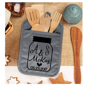 May include: Gray oven mitt with a pocket for utensils. The mitt features a black and white design of a mason jar with the text "A & S McKay 05.23.2017".