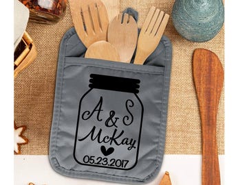May include: Gray oven mitt with a pocket for utensils. The mitt features a black and white design of a mason jar with the text "A & S McKay 05.23.2017".