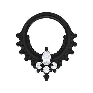 Può includere: Anello per septum nero con un design decorativo e pietre preziose trasparenti. L'anello presenta una gemma a forma di goccia al centro, con tre gemme rotonde più piccole sottostanti. L'anello è in metallo nero e ha una chiusura a cerniera.