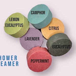 May include: A set of six round shower steamers in various colors and scents: lavender, peppermint, eucalyptus, lemon eucalyptus, camphor, and citrus.  The text "SHOWER STEAMER" is printed below the steamers.