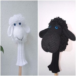 May include: Two crocheted golf club head covers shaped like sheep. One is white with blue eyes and the other is black with blue eyes.