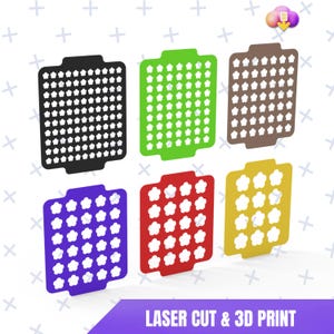 Peut inclure: Six objets rectangulaires colorés, découpés au laser et imprimés en 3D, chacun avec des découpes en forme de fleurs. Les couleurs incluent le noir, le vert, le marron, le violet, le rouge et le jaune. Le texte "LASER CUT & 3D PRINT" est en bas.