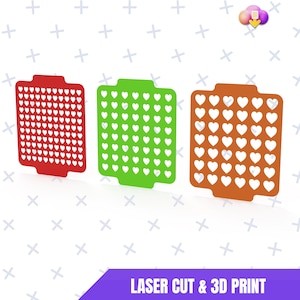 Peut inclure: Trois motifs en forme de cœur découpés au laser, en rouge, vert et orange. Chaque motif a une forme rectangulaire avec une languette en haut et un motif de découpes en forme de cœur. Le texte "LASER CUT & 3D PRINT" est en bas.