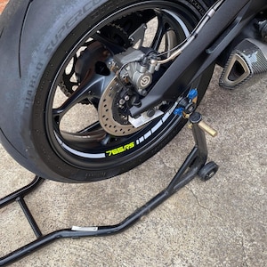 Puede incluir: Una motocicleta negra con un neum&aacute;tico trasero negro y un caballete trasero negro. El neum&aacute;tico tiene una franja blanca y el texto "Diablo Supercorsa 120/70 ZR17 58W" impreso en el lateral. El neum&aacute;tico tambi&eacute;n tiene una franja amarilla con el texto "765RS" impreso en &eacute;l.