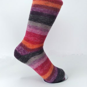 May include: Striped socks in shades of red, orange, purple, grey, and pink. The socks are displayed on a sock form.