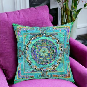 May include: A turquoise and gold throw pillow with a mandala design. The pillow is sitting on a magenta couch.