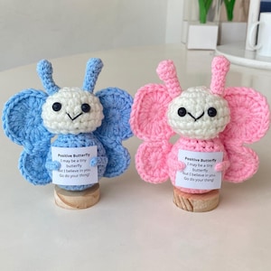 May include: Two crocheted butterfly figurines, one blue and one pink, each holding a small card with the text "Positive Butterfly I may be a tiny butterfly but I believe in you. Go do your thing!"