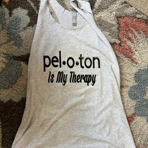 May include: Gray tank top with black text that reads "pel.o.ton is My Therapy".