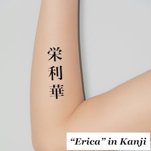 以下が含まれることがあります： 「エリカ」の日本語の漢字のタトゥーをした腕のクローズアップ。タトゥーの下に漢字で「エリカ」と書かれている。