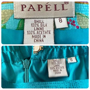 May include: Close-up of two sections of a teal skirt with the brand label "PAPELL". The labels indicate the skirt is made of 100% silk shell and 100% acetate lining. The skirt sizes are 8 and 6.