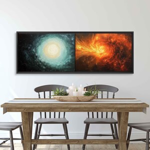 May include: A framed abstract painting depicting two swirling galaxies, one in cool blue and green tones and the other in warm orange and red tones. The painting is displayed on a wall above a wooden table with chairs.